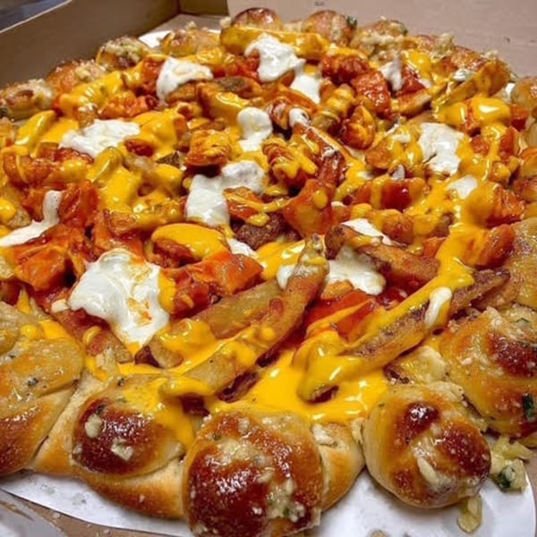 Franco's Italian pizza with a cheesy crust, topped with fries, chicken, and white sauce.