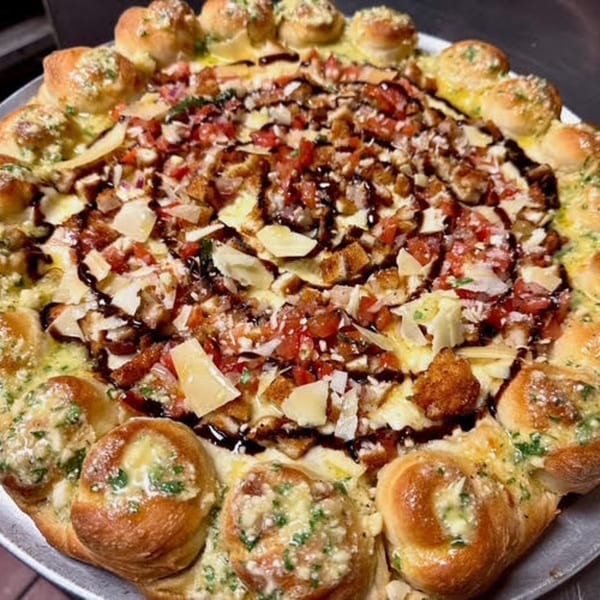 Franco's Italian pizza with a garlic knot crust, topped with diced tomatoes, cheese, and balsamic glaze.